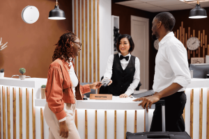 A couple checking in at the hotel reception with a smiling front desk staff member