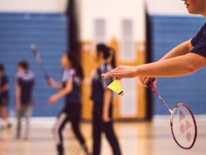 Students playing badminton indoors, showcasing how activities affect air quality standards in school gym environments.