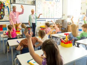 A classroom full of students with teachers, emphasising the importance of air quality checks for healthy learning environments.