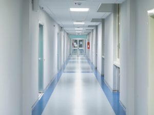 A clean hospital corridor with white walls and a blue floor. Regular air quality audits help maintain optimal hospital conditions.